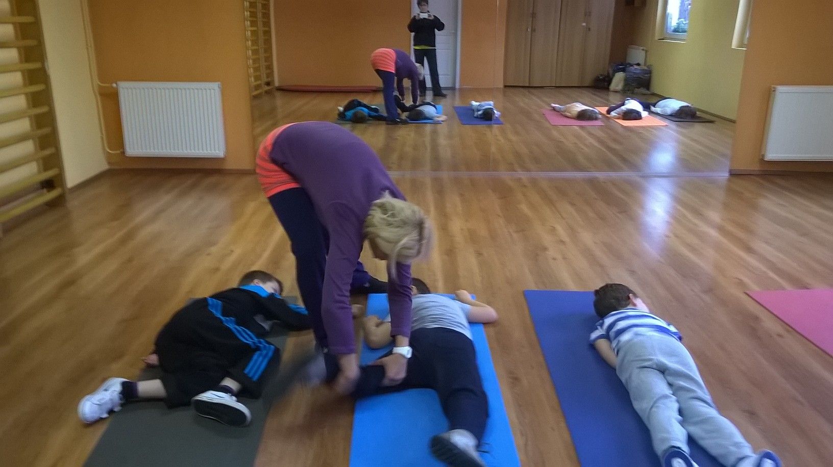 Tammy a szőnyegeken hason fekvő gyerekek mellé hajol, és igazítja a testtartásukat